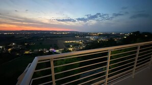A balcony with a metal railing overlooking a cityscape during twilight. - Dimora Filippo (Sant'Elpidio a Mare)