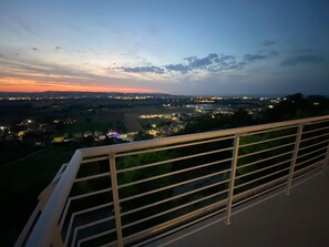 A balcony with a metal railing overlooking a cityscape during twilight. - Dimora Filippo (Sant'Elpidio a Mare)