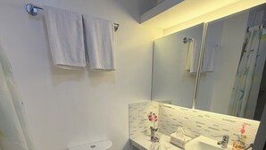 Un bagno con toilette, lavandino e specchio. Due asciugamani sono appesi al muro.