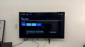 Un televisore a schermo piatto montato su una parete bianca, che mostra il menu di un canale televisivo.
