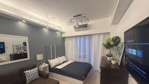 Una camera d'albergo moderna con un letto grande, una TV, un divano e una scrivania.