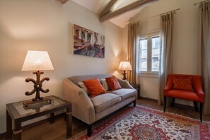 Ein Wohnzimmer mit einer Couch, zwei Lampen, einem Sessel, einem Teppich und einem Gemälde an der Wand.