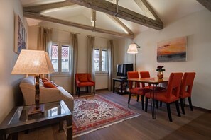 A living room with a sofa, a coffee table, a TV, and a dining area with chairs and a table. - Ca' Barbarina 2 (Venezia)