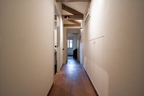 Ein schmales Dielenkorridor mit Holzboden und freiliegenden Holzbalken an der Decke.