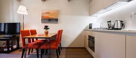 Uma cozinha compacta com área de refeições, televisão de tela plana e um quadro na parede.