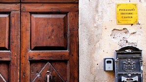A wooden door with a brass knocker and a yellow sign indicating a historic center. - Pitigliano Historic Center (Pitigliano)