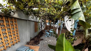 A garden area with a wooden lattice, a seating area with blue chairs, and a table. - Flor e Fruto Retreat - Little Flower House (Rio de Janeiro)