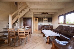 A wooden interior with a dining table, chairs, a sofa, a staircase, and a kitchen area. - Comfortable, large holiday homes with terraces (Wicie)