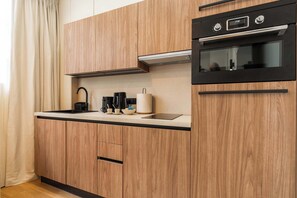 Eine moderne Küche mit Holzausstattung, einem schwarzen Backofen und einem Spülbecken aus Edelstahl.