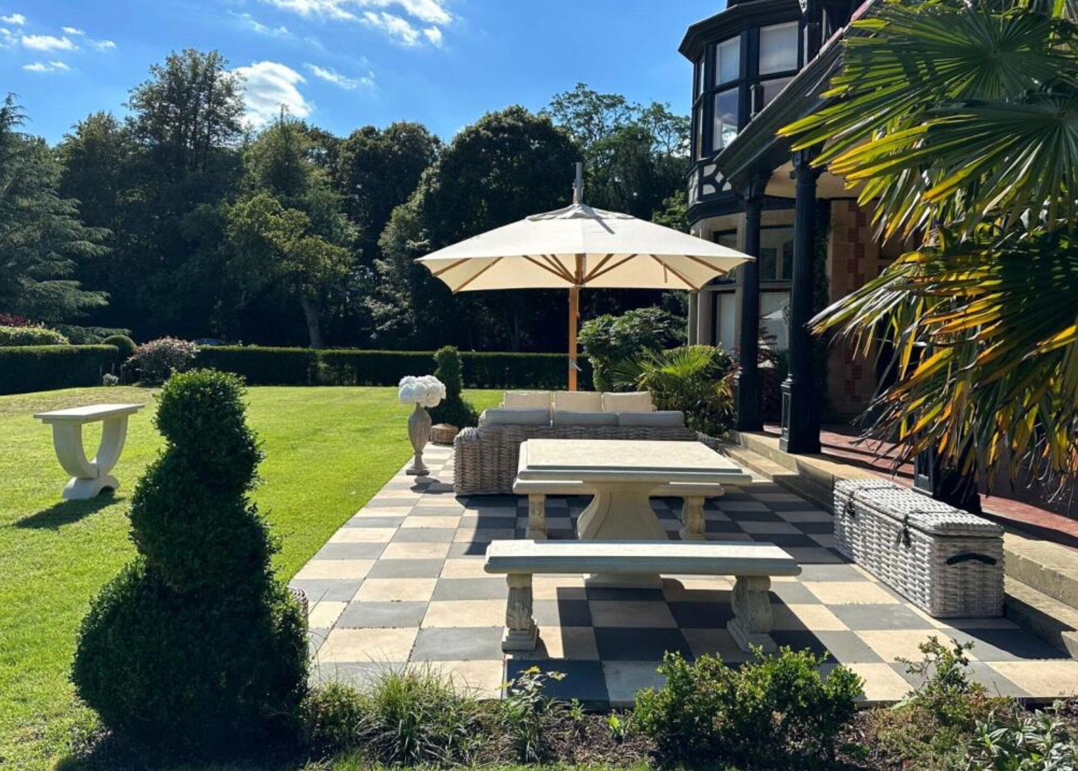 A patio with a checkered floor, a table, and an umbrella.