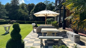 A patio with a checkered floor, a table, and an umbrella.
