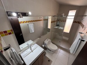 Et badeværelse med vask, toilet og brusekabine.