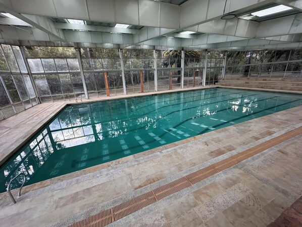 An indoor swimming pool with clear water, surrounded by glass walls and a tiled floor. - D'Acosta Hotel Belencito (Nobsa)