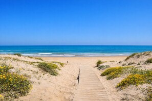 A sandy beach with a wooden pathway leading to the ocean. - Ch1200 in Oliva With 3 Bedrooms and 2 Bathrooms (Oliva)