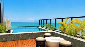Une piscine sur le toit offrant une vue sur l’océan, entourée de plantes tropicales et agrémentée de mobilier d’extérieur.