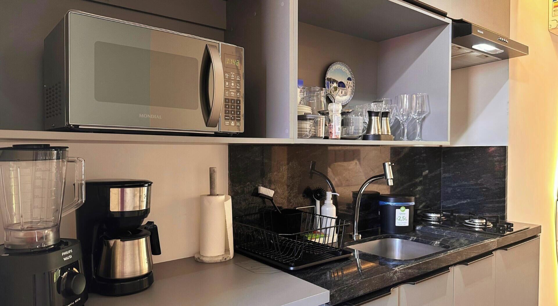 A modern kitchen with a microwave, coffee maker, blender, and a sink.