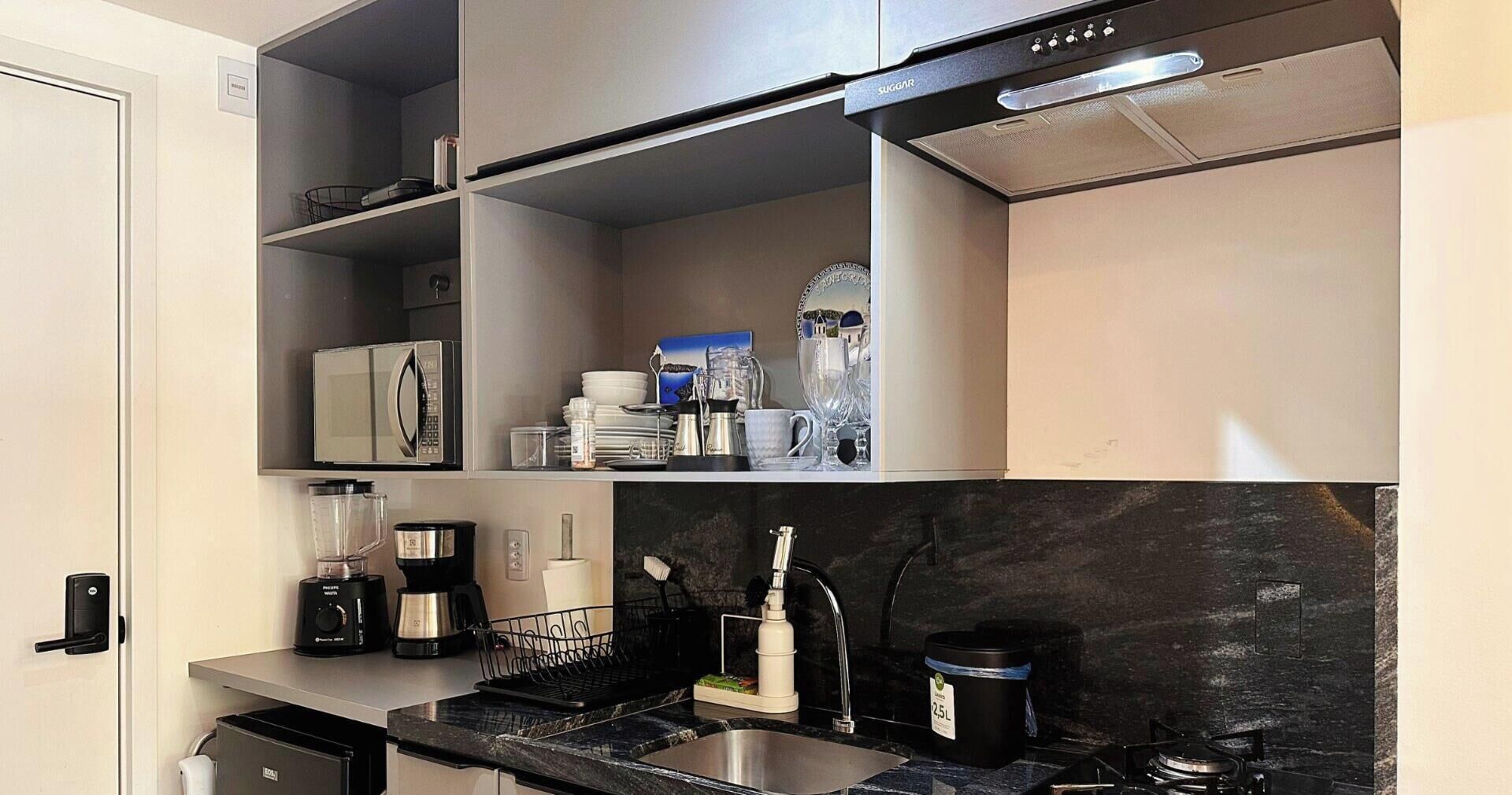 A modern kitchen with a built-in microwave, a coffee maker, and a blender on the countertop.