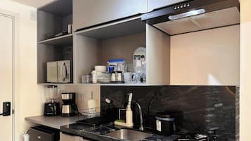 A modern kitchen with a built-in microwave, a coffee maker, and a blender on the countertop.
