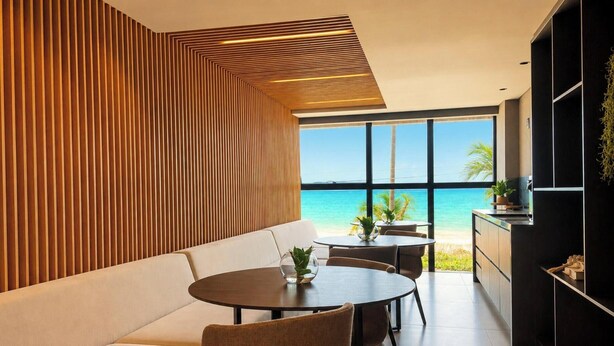 Un interior moderno con sofá, mesa de comedor y sillas, con vistas a una playa.