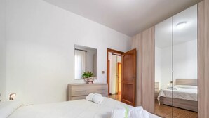 Ein Hotelzimmer mit einem großen Bett, einem Schminktisch, einem Spiegel und einem Kleiderschrank.