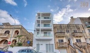 A modern white building with multiple balconies and a sign indicating a no entry for vehicles. - Swieqi, Central 3BR Home w/Fast WIFI & Comfort (Swieqi)