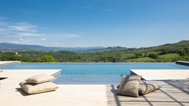 Una piscina con vistas a colinas verdes y un cielo despejado.