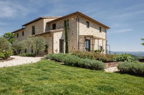 Un bâtiment en pierre avec un toit en tuiles, un chemin de gravier et une pelouse bien entretenue.