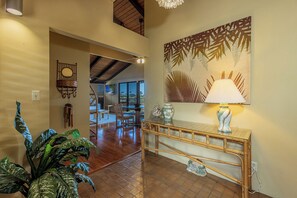 A hallway with a bamboo console table, a wall-mounted lamp, and a large abstract painting. - Wailea Ekolu 408 Spacious Second-Floor Retreat with Panoramic Ocean Views (Kihei)