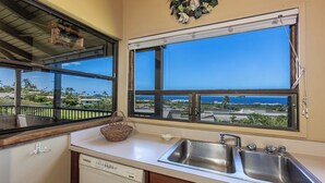 Una cocina con un amplio ventanal, lavavajillas y un lavabo.