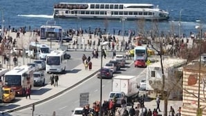 Una zona marítima concurrida con un ferry, vehículos y peatones.