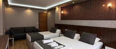A modern hotel room with a large bed, a sofa, and a desk.
