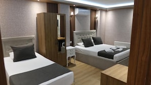 Habitación de hotel con dos camas, un armario de madera, un escritorio pequeño y un espejo.