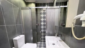 Un baño pequeño con inodoro, lavabo y cabina de ducha.