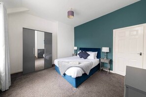 Une chambre à coucher avec un lit, des tables de chevet, une armoire et une porte.