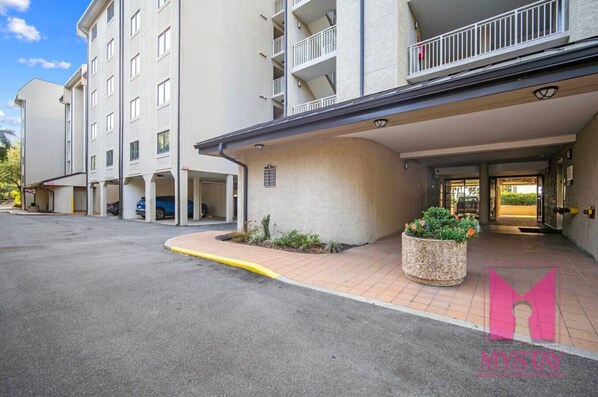 A multi-story hotel with a covered entrance, outdoor parking, and a landscaped area with planters. - MyStay at 136 Shorewood | Ocean + Pool Views | Walk to Coligny | Sleeps 6 (Hilton Head Island)