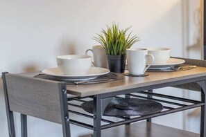 A dining table with white cups, saucers, and a potted plant. - The Wishy - 2 Bedroom Flat in Newmains (Newmains)
