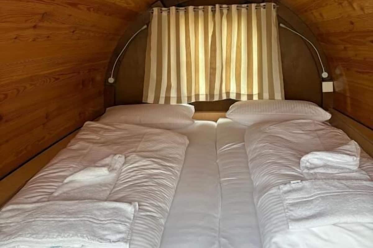 Un intérieur chaleureux, avec des murs en bois, un lit, des rideaux et un luminaire au plafond.