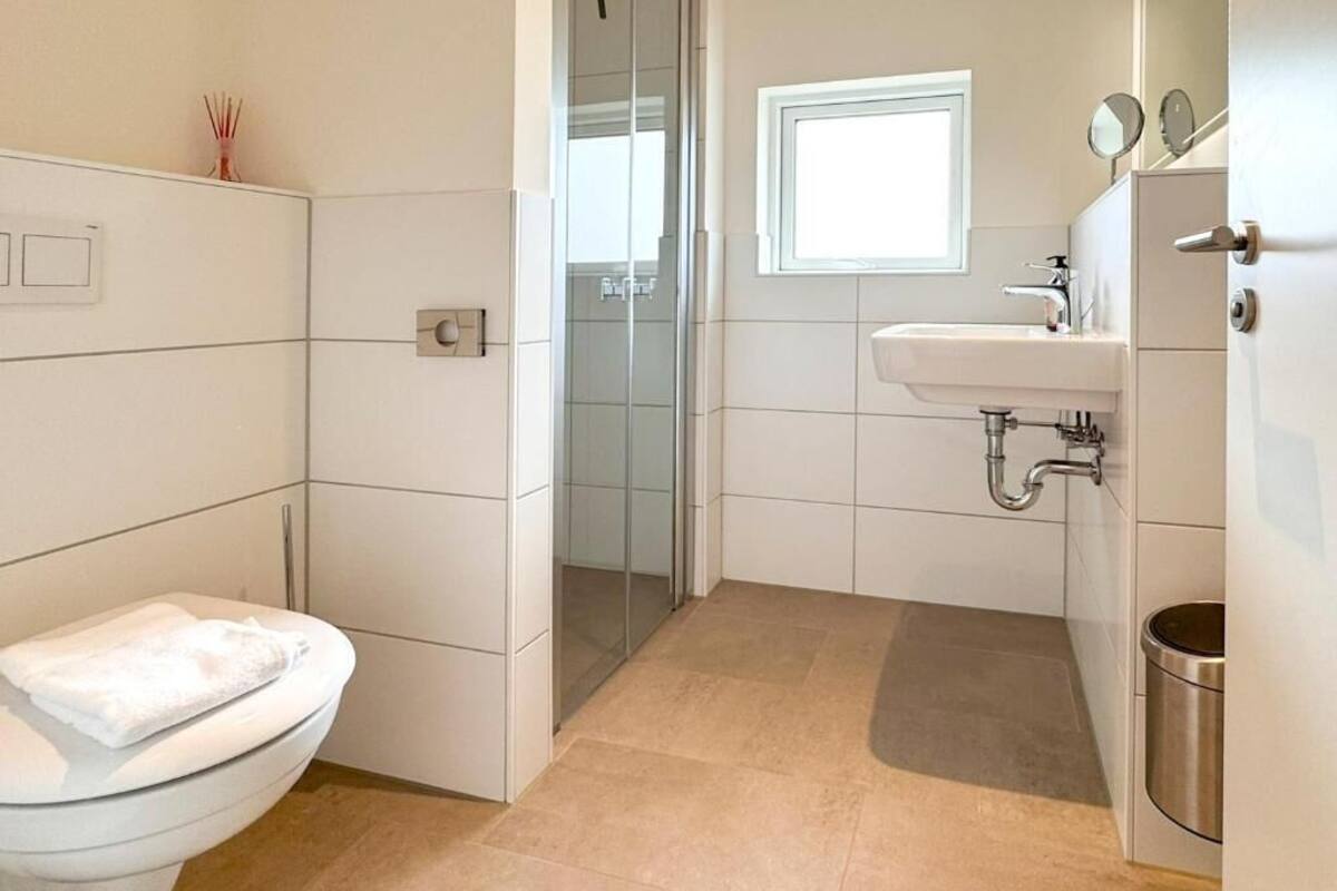 Une salle de bain avec des toilettes, un lavabo, une douche et une fenêtre.