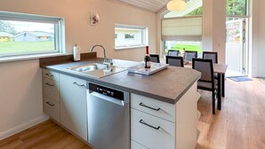 Une cuisine moderne équipée d’un lave-vaisselle, d’un évier et d’un coin repas avec des chaises et une table.