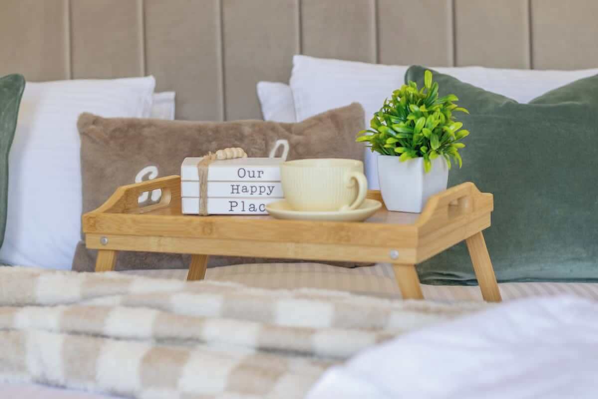 Una cama con una bandeja que sostiene una taza y un letrero que dice 'Our Happy Place'.