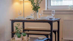 A dining table set with white plates, glasses, and a vase with green foliage. - Raeburn House- 3 Bedrooms, 2 Bathrooms in Hamilton (Hamilton)