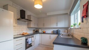 A modern kitchen with white cabinets, a built-in oven, a microwave, and a kettle. - Raeburn House- 3 Bedrooms, 2 Bathrooms in Hamilton (Hamilton)