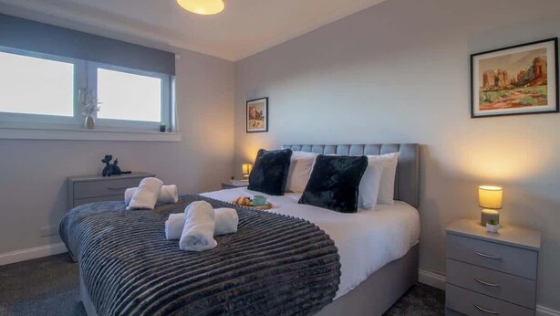 A bedroom with a bed, bedside tables, a window, and artwork on the walls. - Raeburn House- 3 Bedrooms, 2 Bathrooms in Hamilton (Hamilton)