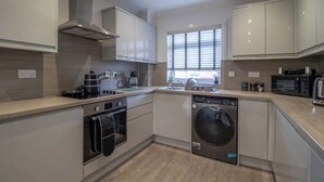A modern kitchen with built-in appliances, a dishwasher, and a large window. - Catriona House - 3 Bedroom house in Motherwell (Holytown)
