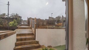 Una scala conduce a un balcone da cui si scorge un giardino e un edificio sullo sfondo.