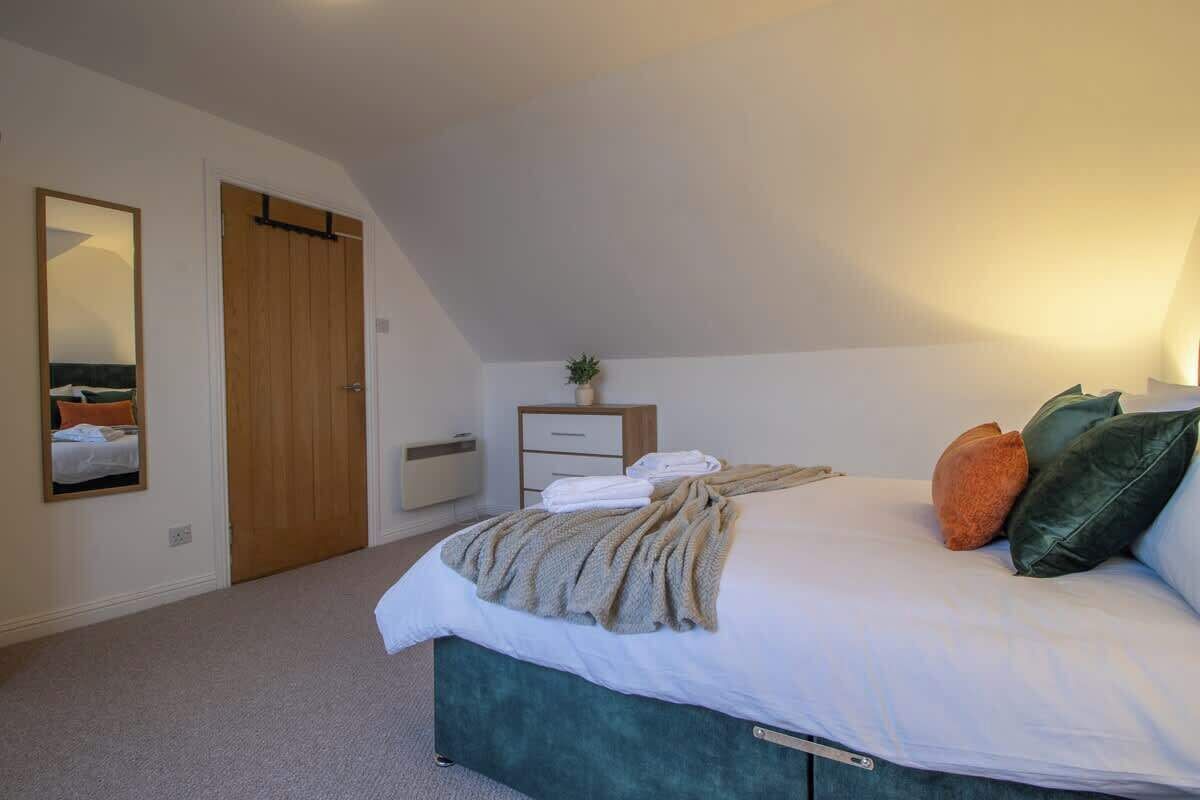 Ein Schlafzimmer mit Bett, Nachttisch, Spiegel, Kleiderschrank und einer kleinen Pflanze.