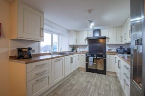 A modern kitchen with white cabinetry, a black stove, and a stainless steel refrigerator.