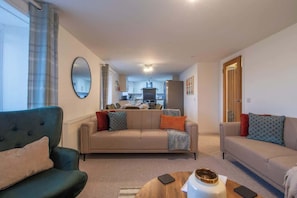 A living room with a sofa, a coffee table, and a dining area in the background.