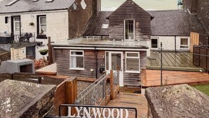 Un edificio chiamato LYNWOOD con facciata in legno, un ingresso chiuso da cancello e un piccolo portico.