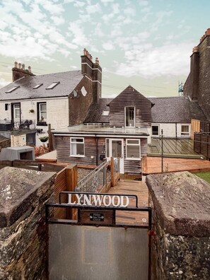 A building named LYNWOOD with a wooden facade, a gated entrance, and a small porch area.
